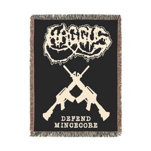 May include: Black woven blanket with a cream-colored graphic design. The design features a stylized logo above two crossed rifles, with the words "DEFEND MINCECORE" below. The blanket has a fringed edge.