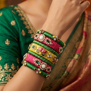 May include: A stack of colorful bangles in shades of green, pink, and yellow, adorned with pearls and gemstones. The bangles are stacked on top of each other, creating a vibrant and eye-catching display. The jewelry is a beautiful accessory.