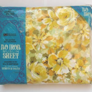 May include: A packaged double-size fitted sheet with a floral pattern in yellow, white, and green. The packaging is clear plastic with a blue label that reads "No Iron Muslin Sheet" and "Designed to fit 54 x 76 mattress".