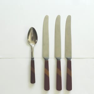 May include: A set of four pieces of flatware consisting of one silver-toned spoon and three silver-toned knives. Each handle features a dark maroon base color with a diagonal stripe of light brown running across the center of the handle.