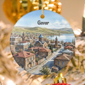 May include: Round ceramic ornament featuring a watercolor painting of Gavar, Armenia. The image depicts a cityscape with buildings, churches, and a lake under a blue sky. The word "Gavar" is printed at the top.