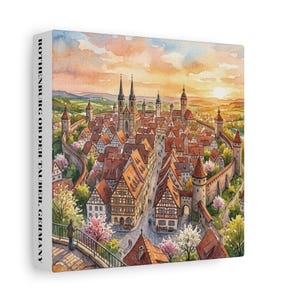 Peut inclure: Une impression sur toile carrée présentant une illustration à l'aquarelle de Rothenburg ob der Tauber, en Allemagne. La scène montre une ville médiévale fortifiée avec des maisons à colombages, des toits rouges et des tours sous un ciel au coucher du soleil. Le texte ROTHENBURG OB DER TAUBER, GERMANY est imprimé verticalement sur le côté.