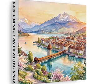 May include: A square canvas print featuring a watercolor painting of Lucerne, Switzerland, with the text LUCERNE, SWITZERLAND printed on the side. The scene depicts a wooden bridge, a lake, historic buildings, and snow-capped mountains at sunset.