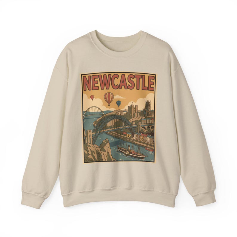Retro graphic on a sand-colored sweatshirt showing the Newcastle landscape with the Tyne Bridge and hot air balloons.