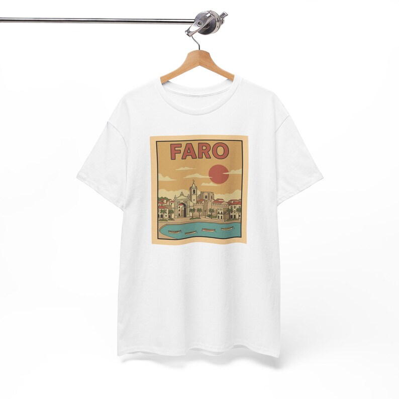 May include: White t-shirt featuring a vintage-style graphic of Faro, Portugal. The design includes the word "FARO" above a red sun, with a detailed illustration of buildings, water, and boats in shades of beige, brown, and blue.