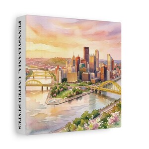 Peut inclure: Une impression sur toile carrée représentant une peinture à l'aquarelle de la ligne d'horizon de Pittsburgh au coucher du soleil. La scène inclut des ponts jaunes, un confluent de rivières et des bâtiments. Le côté affiche PENNSYLVANIA, UNITED STATES.