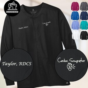 Könnte beinhalten: Schwarze Langarm-Arztkitteljacke mit gesticktem Text "Taylor, RDCS" und "Cardiac Sonographer" mit einer Herzgrafik. Zusätzliche Farboptionen werden im Hintergrund angezeigt.