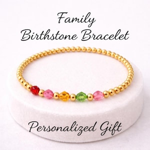 May include: A gold beaded bracelet with colourful birthstone accents. The bracelet features red, pink, yellow, green, and pink gemstones. Text on the image reads "Family Birthstone Bracelet" and "Personalized Gift".
