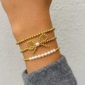 Conjunto de pulseras chapadas en oro de 18 quilates: lazo de perlas y detalles de cuentas.