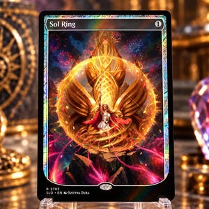 Puede incluir: Una carta coleccionable rectangular titulada Sol Ring que presenta una esfera dorada central con una figura alada, rodeada de fuegos artificiales y terreno rocoso oscuro. La carta tiene un borde negro con un acabado holográfico y texto.