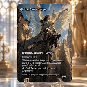 May include: A rectangular trading card titled Giada, Font of Hope, featuring an illustration of an angel with large wings perched on a stone structure. The card text includes Legendary Creature - Angel, ability descriptions, and a 2/2 power and toughness rating. The card is displayed on a clear plastic stand.