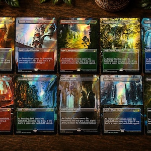 May include: A collection of ten rectangular Magic: The Gathering trading cards arranged in two rows. Each card features vibrant, full-art fantasy landscape illustrations with a holographic foil finish, displaying specific land names and game text.