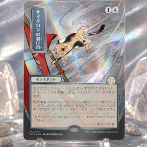 May include: A holographic Magic: The Gathering trading card titled "Cyclonic Rift" in Japanese. The card features an illustration of a calico cat leaping over a red flag against a swirling, metallic background. Text includes game rules and flavor text.