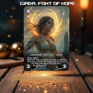 May include: A fantasy trading card featuring a woman with golden wings and a halo. The card is titled "Giada, Font of Hope" and has a mana cost of 1 white. The card text reads: "Flying, vigilance. Each other Angel you control enters with an additional +1/+1 counter on it for each Angel you already control. Tap Add White. Spend this mana only to cast an Angel spell."