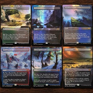 May include: Ten rectangular Magic: The Gathering trading cards arranged in two rows. Each card features full-art landscape illustrations with a holographic foil finish, displaying various terrain types and game text instructions for land cards.