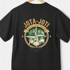 Könnte beinhalten: Schwarzes T-Shirt mit einem kreisförmigen Design. Die Grafik enthält den Text "JOTA-JOTI" und "Connecting Scouts Worldwide". Ein Kompass, ein Globus, ein Funkturm und das Datum "Oktober 2025" sind ebenfalls abgebildet.