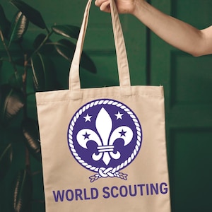 May include: A beige tote bag with a blue and white World Scouting emblem. The emblem features a fleur-de-lis, stars, and a rope border. The words "WORLD SCOUTING" are printed in blue below the emblem.