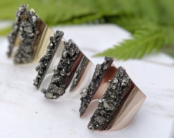 May include: Three gold, silver, and rose gold rings with a triangular shape and a textured surface. The rings are made of metal and have a natural stone inlay.