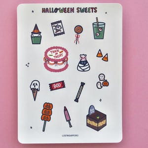 May include: A white sticker sheet titled HALLOWEEN SWEETS featuring various illustrations including a cupcake with a witch hat, a lollipop, a green drink with eyeballs, a cake with TRICK OR TREAT text, candy corn, a ghost ice cream, and a tombstone cake.