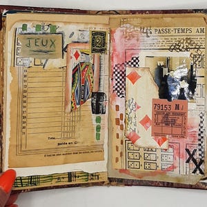 May include: Open journal with collaged pages featuring vintage ephemera. Includes playing card imagery, a postage stamp, and the word "JEUX". The pages are adorned with red, black, and white accents, and a ticket stub.