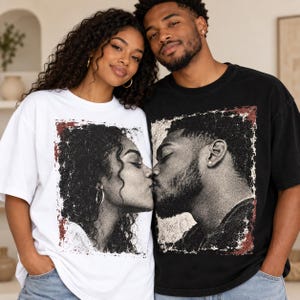 May include: A white t-shirt and a black t-shirt, each featuring a large, square, distressed-style graphic print of a couple kissing in profile. The print has a textured, vintage appearance with dark ink tones and subtle red accents along the edges.