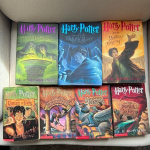 May include: A collection of seven Harry Potter books by J.K. Rowling, including The Half-Blood Prince, Order of the Phoenix, Deathly Hallows, Goblet of Fire, Sorcerer's Stone, Prisoner of Azkaban, and Chamber of Secrets with illustrated covers.