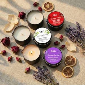 May include: An overhead shot displays several black massage candles with white wax, surrounded by dried flowers and citrus slices. The candles have labels with the text "E&D Massage Candle" and various scents like "Jasmine" and "Lavender".