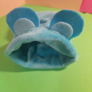 May include: A light blue hooded pet sweater with ear-like flaps on the top.