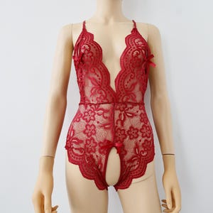 May include: Red lace bodysuit with a plunging neckline and a cutout at the crotch.
