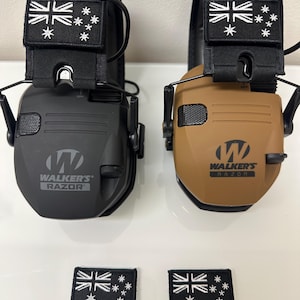 May include: Two black and tan Walkers Razor electronic earmuffs with a black and white Australian flag patch on each earcup. The earmuffs are on a white surface with two smaller black and white Australian flag patches below them.