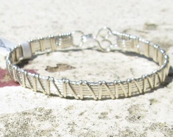 May include: A silver wire wrapped bracelet with a simple clasp.