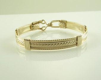Könnte beinhalten: Ein goldenes Armband mit geflochtenem Design und einem Verschluss.