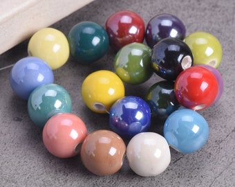 Puede incluir: Una cadena de cuentas de cerámica de colores en varios tonos de azul, verde, amarillo, rojo y marrón. Las cuentas son redondas y tienen un acabado brillante.