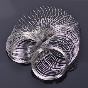 May include: A silver metal spring coil, also known as a slinky, is coiled up in a spiral shape. The spring is made of many individual loops of wire.