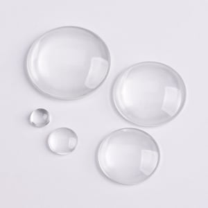 May include: Four clear glass cabochons of varying sizes. The largest cabochon is approximately 5 cm in diameter, while the smallest is about 1.25 cm in diameter.