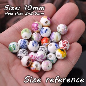 May include: A collection of 20 white ceramic beads with colorful floral patterns. The beads are 10mm in diameter with a 2-2.5mm hole. Size: 10mm Hole size: 2~2.5mm
