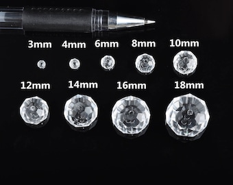 Könnte beinhalten: Sortiment aus klaren Glaskristallperlen in verschiedenen Größen von 3 mm bis 18 mm. Die Perlen sind in Reihen auf einer schwarzen Oberfläche angeordnet.