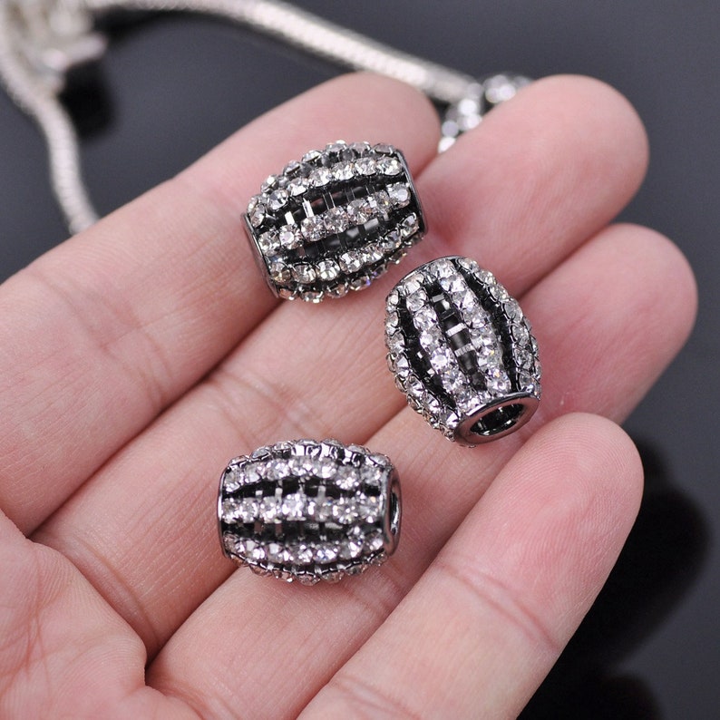 May include: Three silver-toned barrel-shaped beads with clear rhinestones set in a grid pattern.