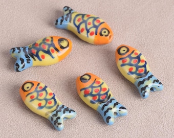 May include: Five ceramic fish figurines. Each fish has a yellow body, orange head, and blue tail. The fish are decorated with red and blue patterns. The figurines are small and decorative.