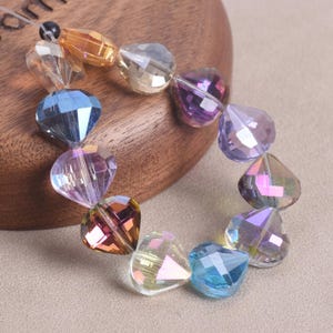 Conjunto de 10 contas de cristal facetadas, brilhantes e coloridas, em formato de vieira, medindo 11 x 12 mm, ideais para confecção de joias e projetos DIY.