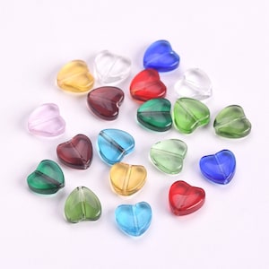 Puede incluir: Surtido de cuentas de vidrio en forma de corazón en varios colores, incluyendo transparente, rojo, azul, verde, amarillo y morado. Las cuentas son perfectas para la elaboración de joyas, manualidades y decoración del hogar.