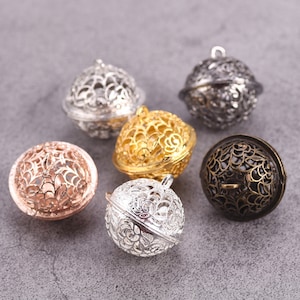 May include: Six ornate metal bells in various finishes, including silver, gold, rose gold, and black. The bells have a delicate, intricate design and are perfect for adding a touch of elegance to jewellery or crafts.