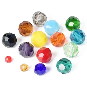 Puede incluir: Una colección de cuentas facetadas en varios colores, incluyendo rojo, amarillo, azul, verde y naranja. Las cuentas son redondas con múltiples superficies planas, creando un efecto brillante. Algunas cuentas tienen un agujero para ensartar.