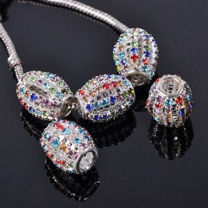 May include: A silver chain with four oval-shaped beads. Each bead is covered in colorful rhinestones.