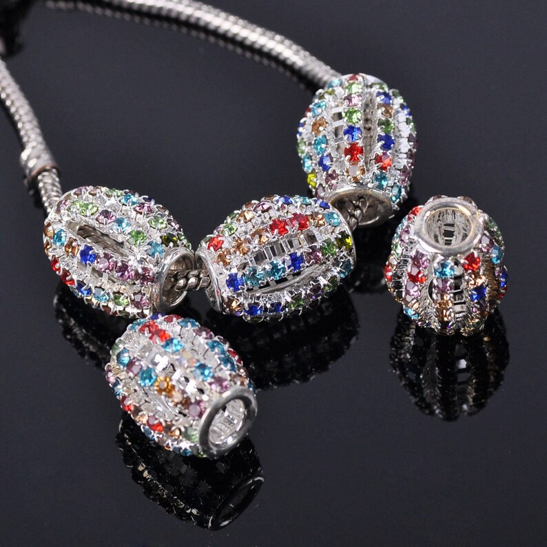 May include: A silver chain with four oval-shaped beads. Each bead is covered in colorful rhinestones.