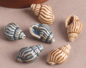 May include: A collection of six ceramic beads shaped like spiral seashells. Three beads feature a glossy tan and brown striped finish, while the other three display a glossy blue and grey striped pattern. Each bead has a small hole for threading.