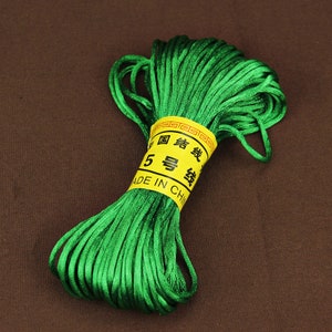 May include: A spool of bright green, thin, satin cord. The cord is wrapped around a yellow label with Chinese characters and the text "MADE IN CHINA".