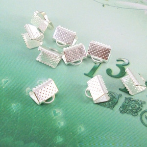 May include: Silver metal clasps for jewelry making. The clasps are small and have a textured surface.
