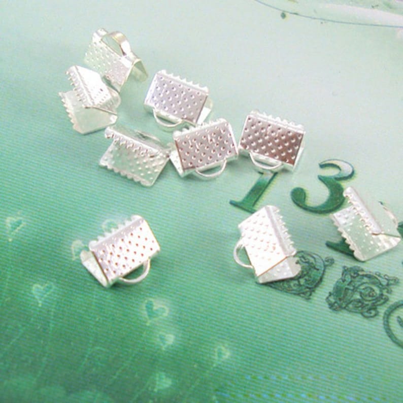 May include: Silver metal clasps for jewelry making. The clasps are small and have a textured surface.