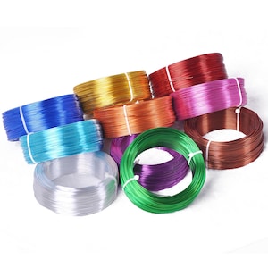 May include: Assortment of colorful wire spools in various colors including gold, red, pink, blue, turquoise, orange, copper, purple, and green.